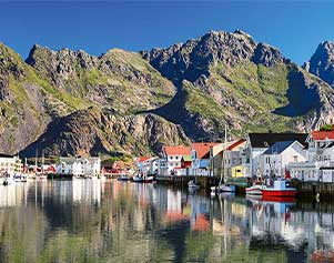 Henningsvær liegt vor einer malerischen Bergkulisse auf den Lofoten.