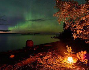 Paar am Feuer bei der Nordlichterbeobachtung in Schwedisch Lappland - Brändön Lodge Graeme Richardson