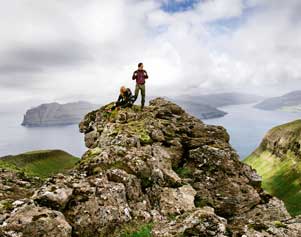 Wanderer auf einer Bergspitze auf den Färöer Inseln