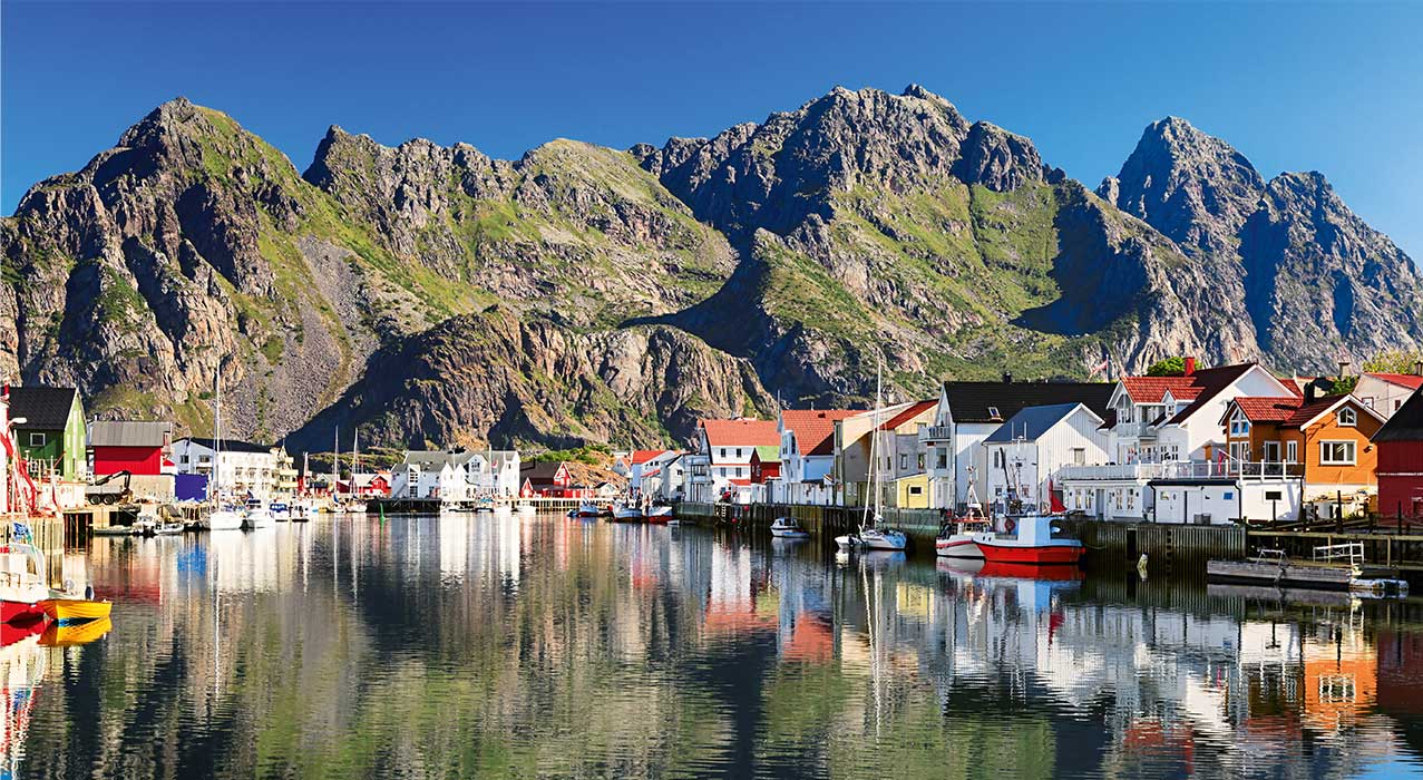 Henningsvær liegt vor einer malerischen Bergkulisse auf den Lofoten.