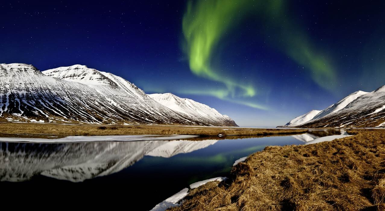 Nordlichter erleben Sie bei dieser Gruppenreise, wie hier über einem Fjord in Island